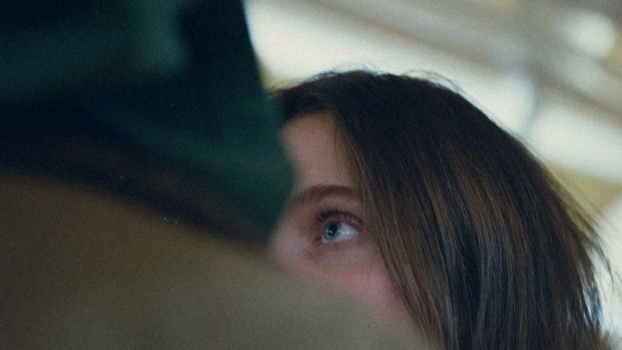 Close-up of her eye, half hidden behind a blurred shoulder.